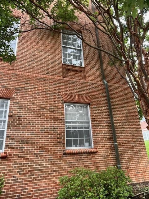 A brick building with a lot of windows and a tree in front of it.