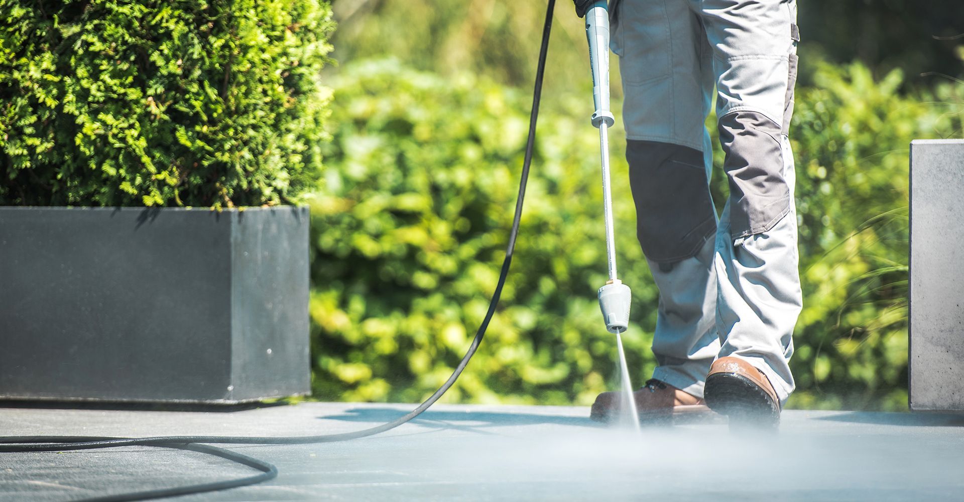 A man is using a high pressure washer to clean a patio.