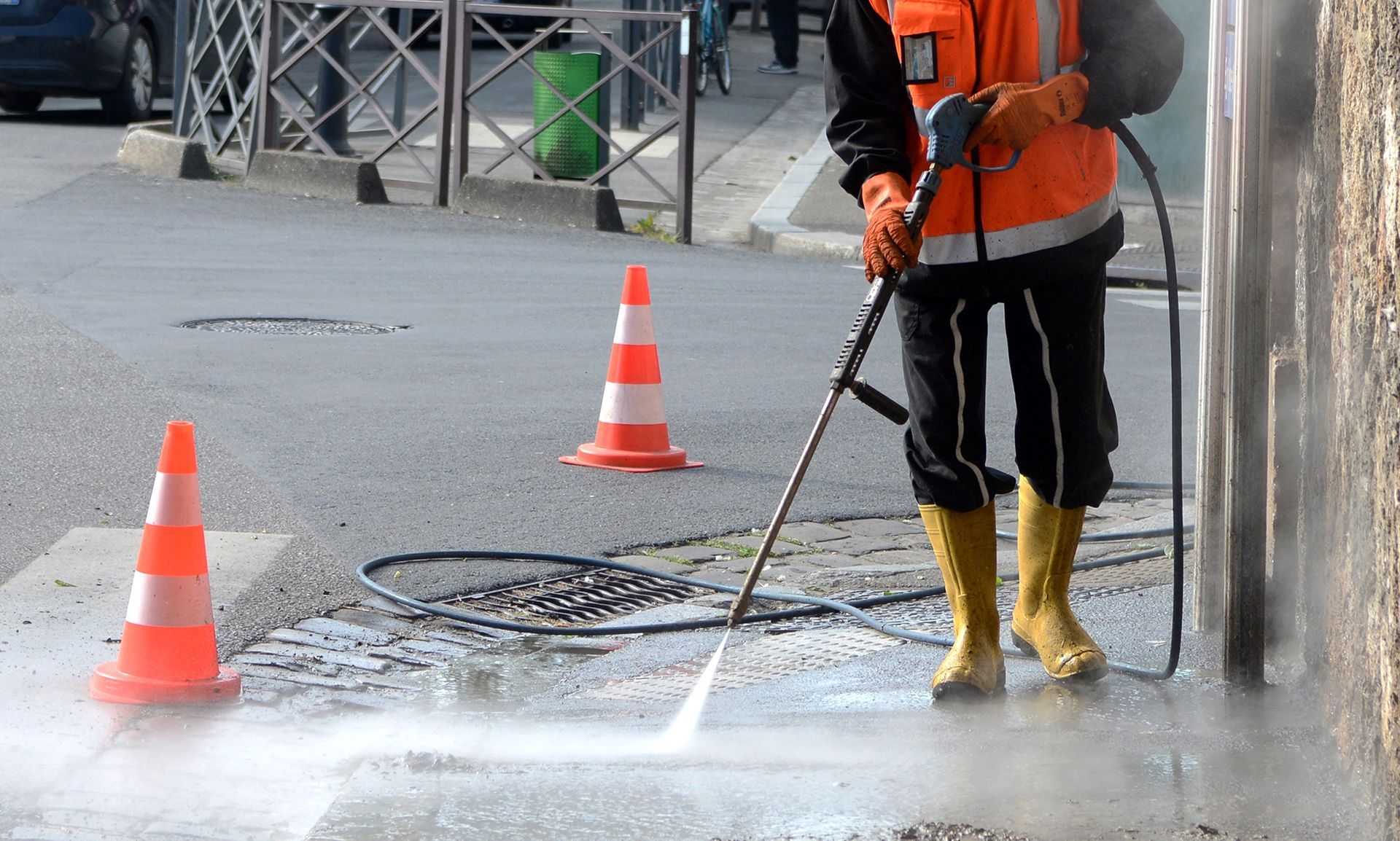 A man is cleaning the sidewalk with a high pressure washer