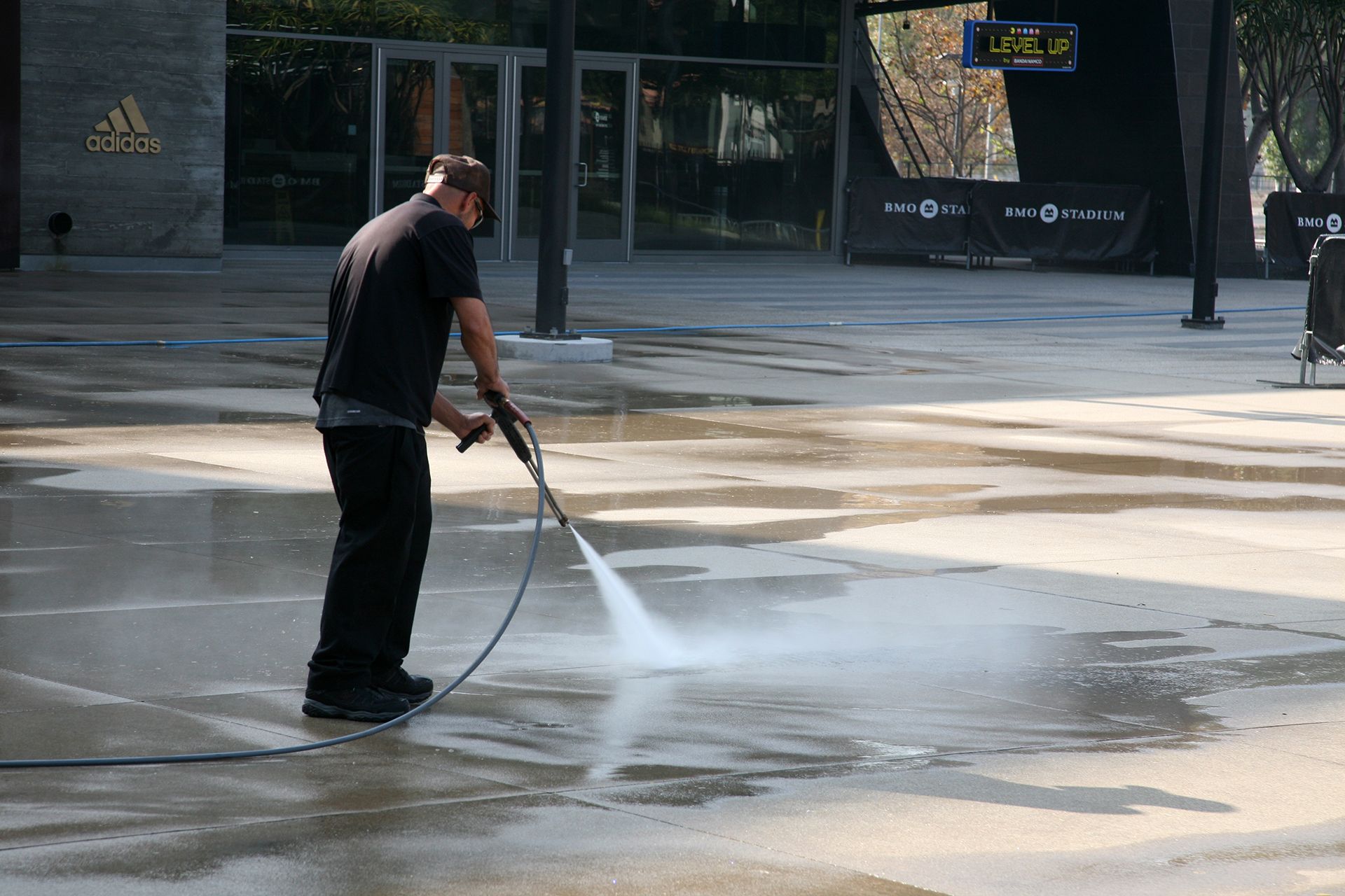 A man is using a high pressure washer to clean a concrete surface.