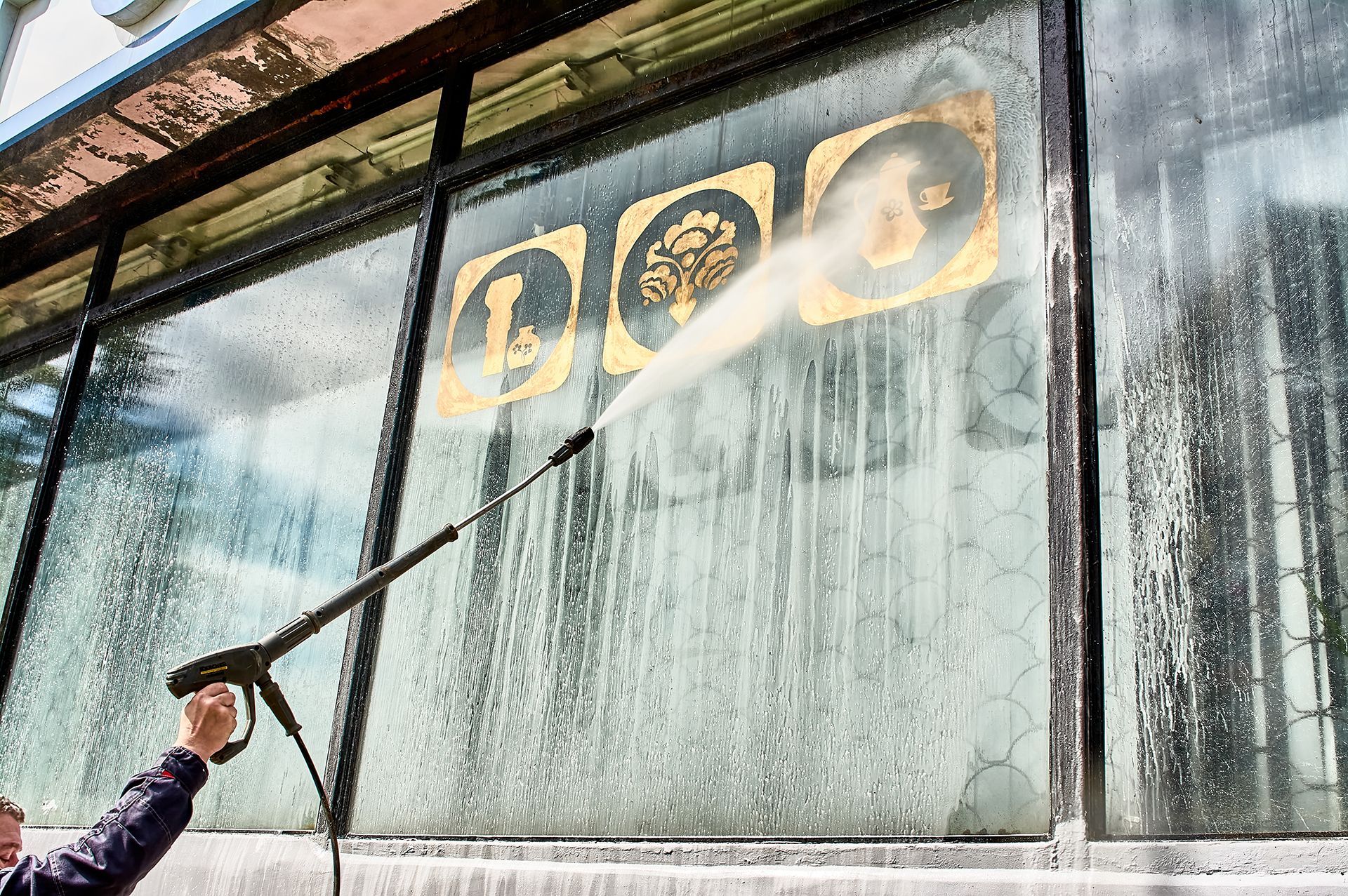 A man is cleaning a window with a high pressure washer.
