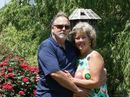 A man and a woman are posing for a picture in front of a birdhouse.