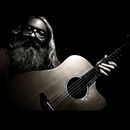 A man with a beard is playing an acoustic guitar