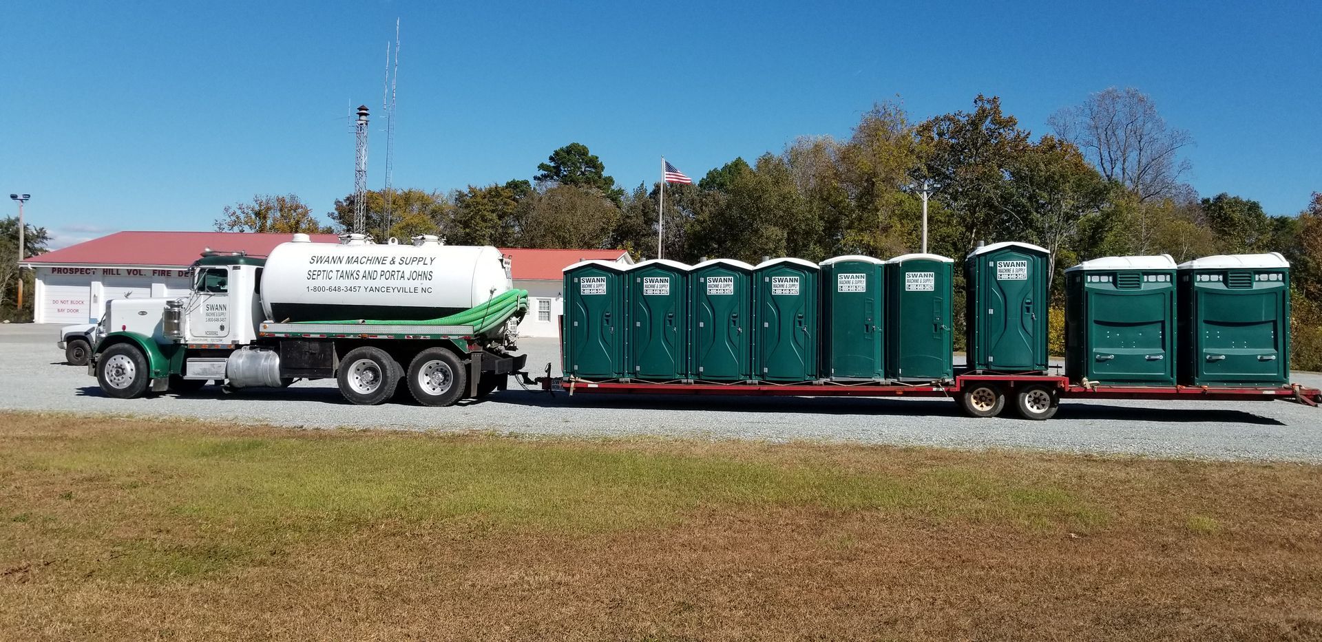 A truck with a trailer full of green portable toilets