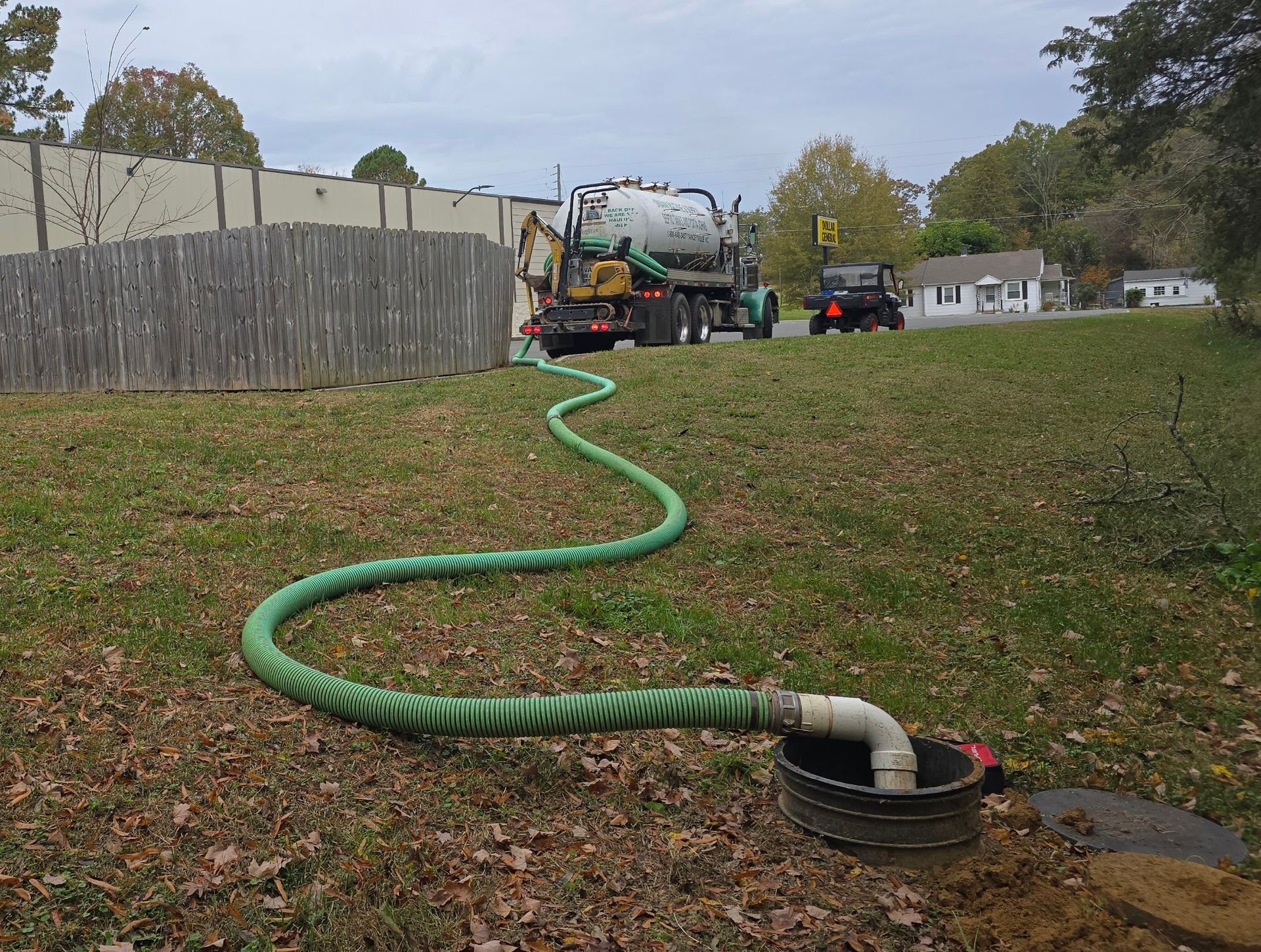 A septic tank is being pumped with a green hose.