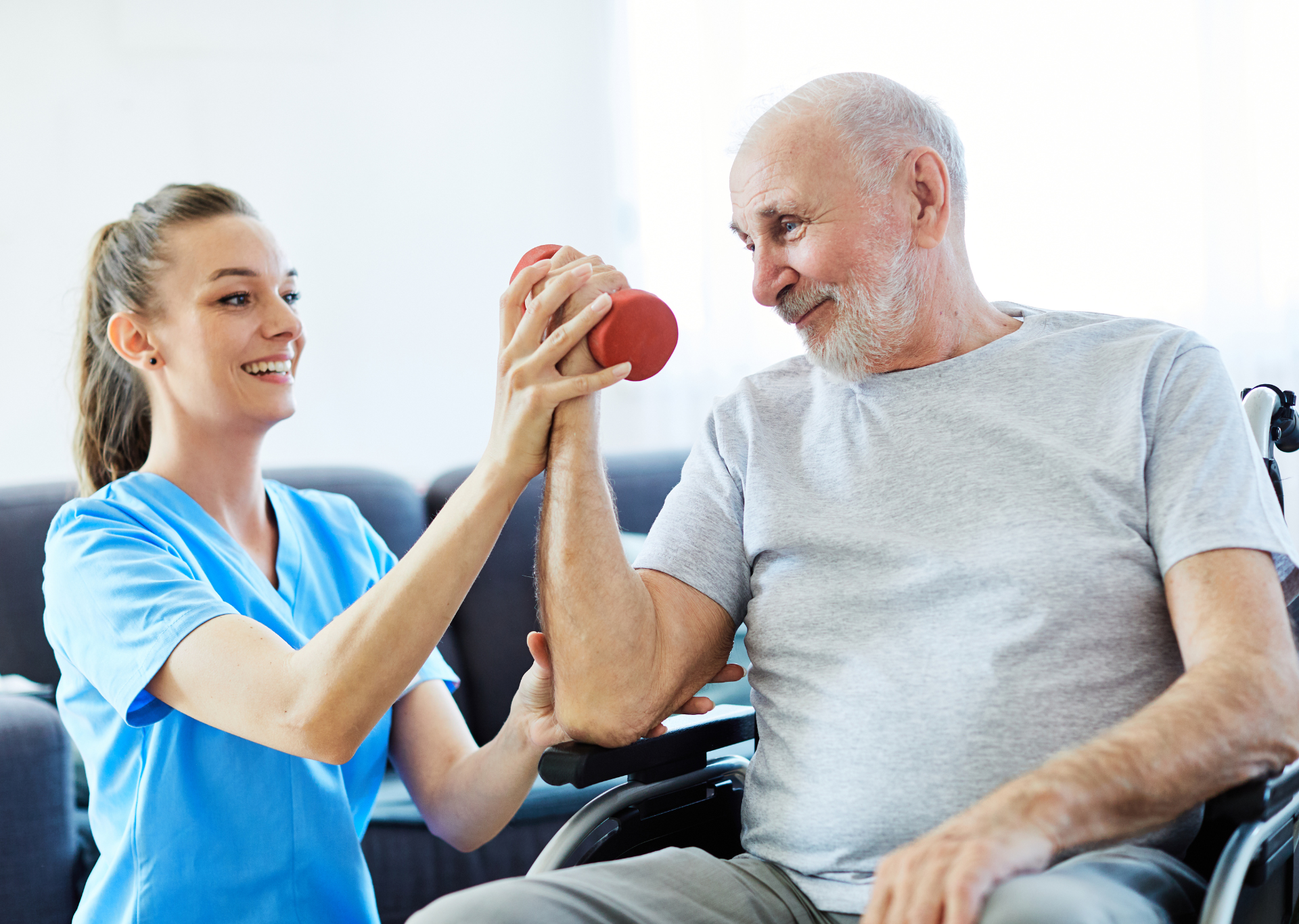 personal care worker with senior man with dumbell in hand