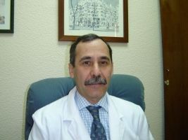 Un hombre con bata blanca y corbata está sentado en una silla.