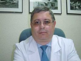 Un hombre con bata blanca y corbata está sentado en una silla.