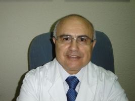 Un hombre con bata blanca y corbata está sentado en una silla.