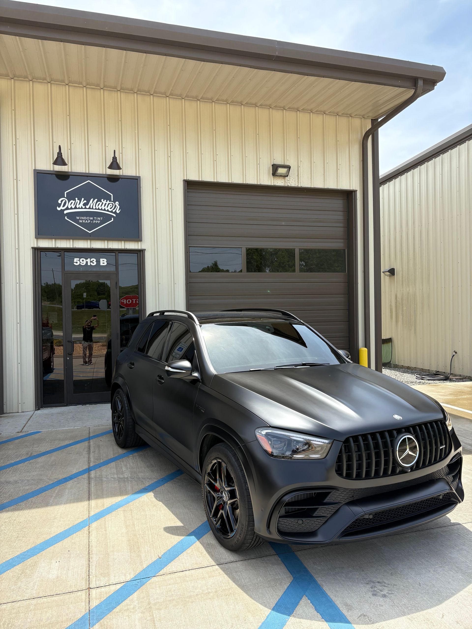 Black matte Mercedes SUV parked outside a shop with a sign that reads 