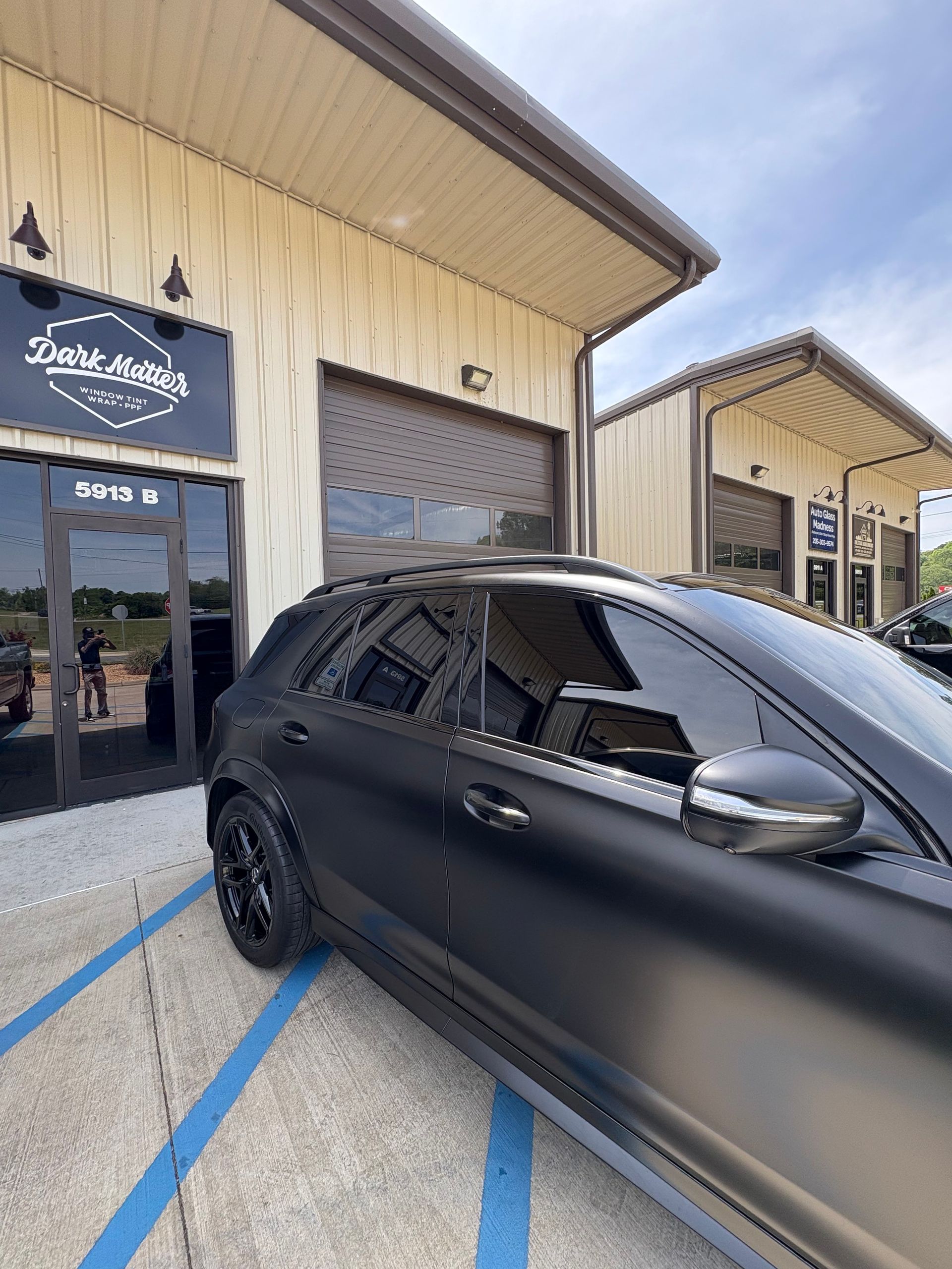 Matte black car parked outside a building with tinted windows. 
