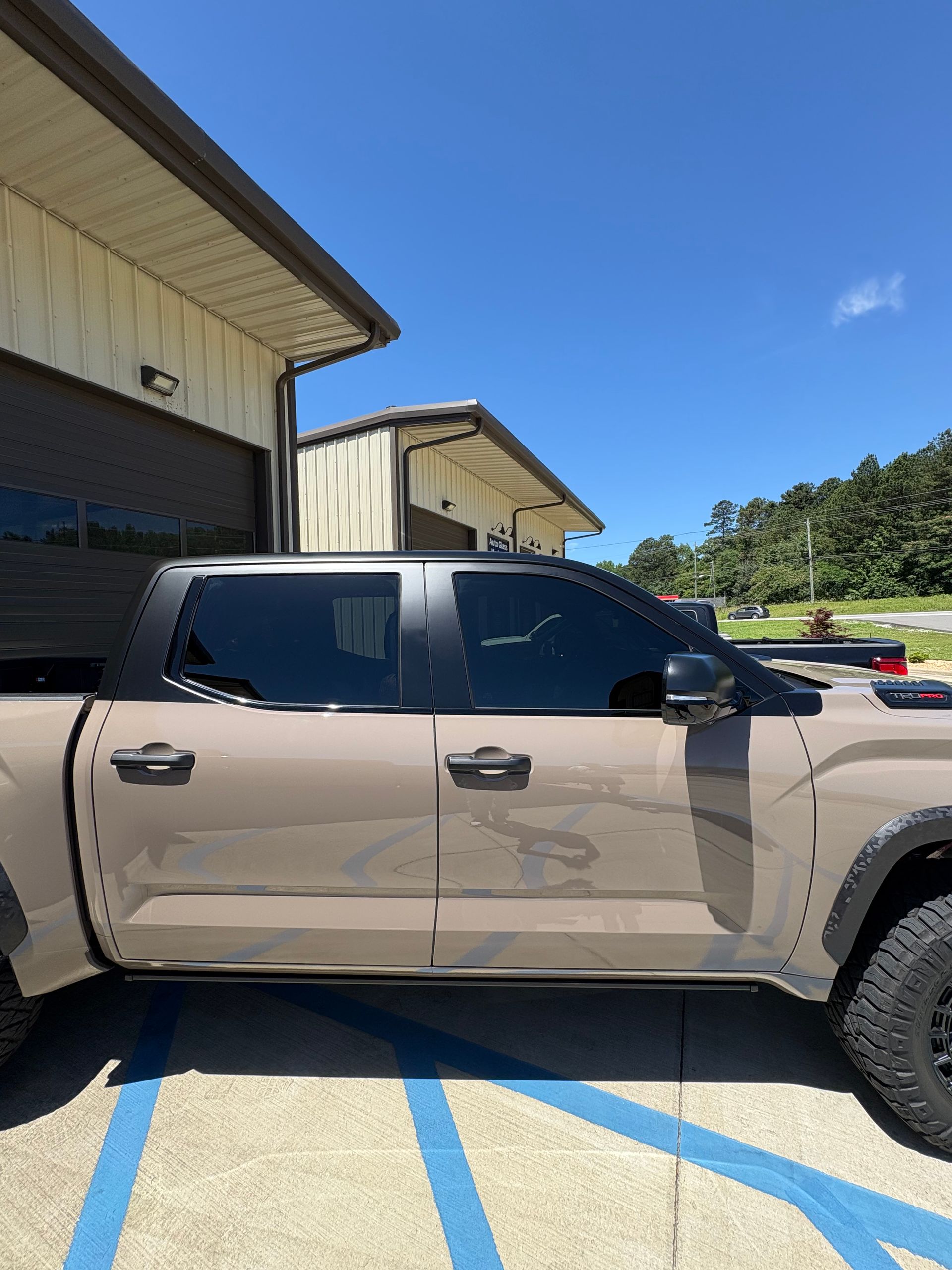 Tan pickup truck with tinted windows parked near a building on a sunny day.