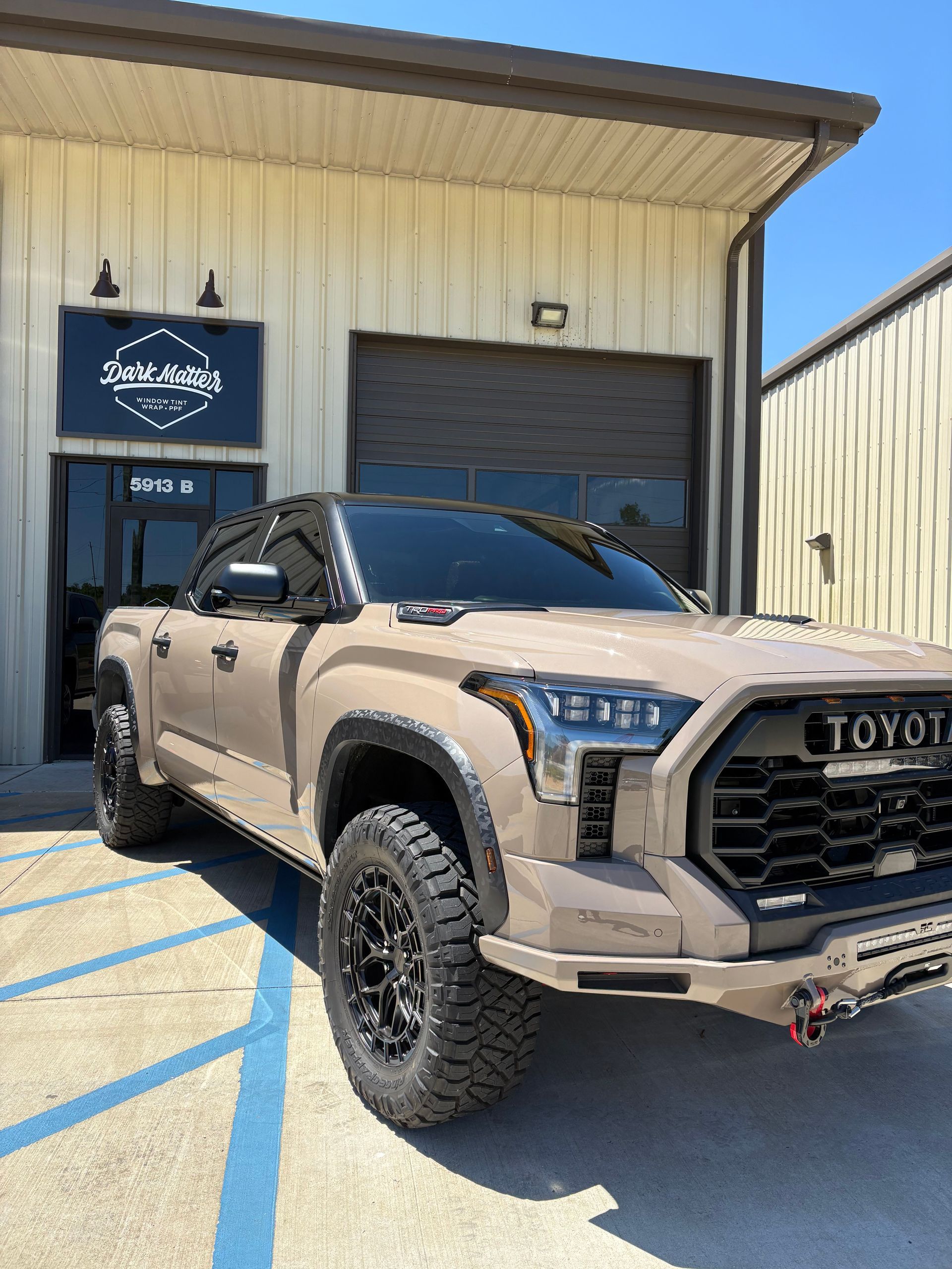 Tan Toyota Tundra truck parked outside a building with the business sign 