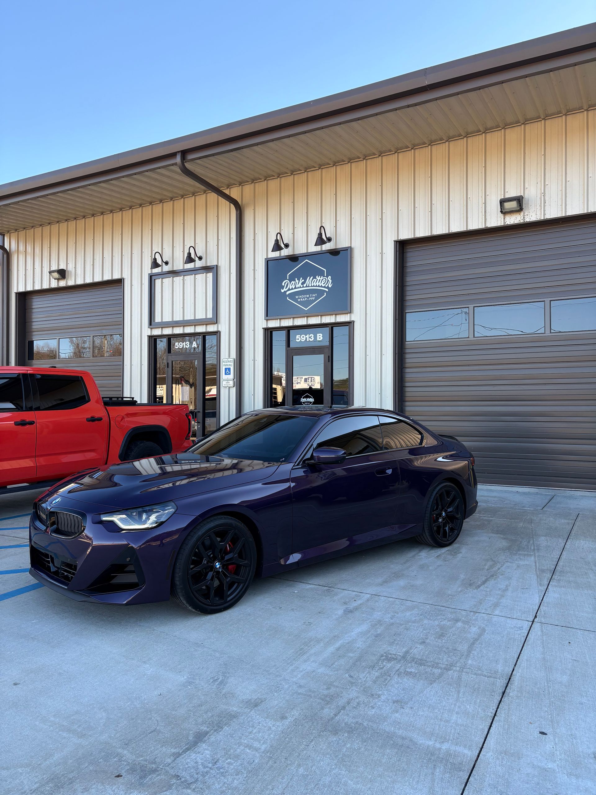 Purple sports car parked outside a building with the business sign 