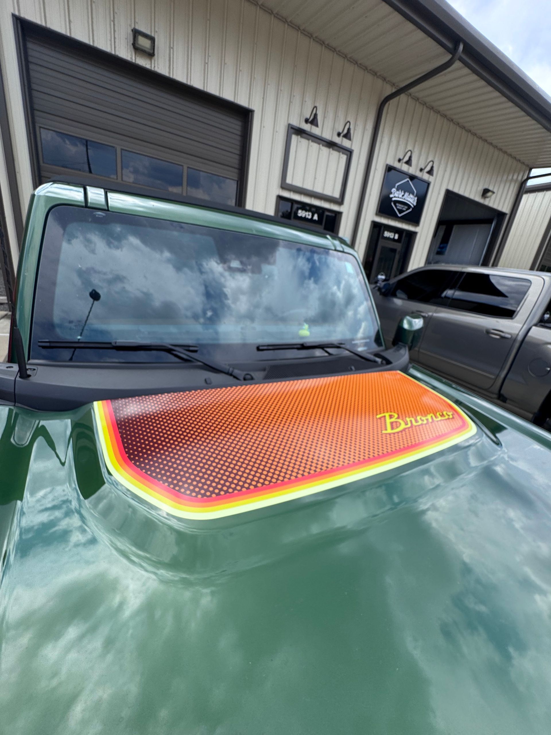 Green Ford Bronco hood with orange and yellow graphic.