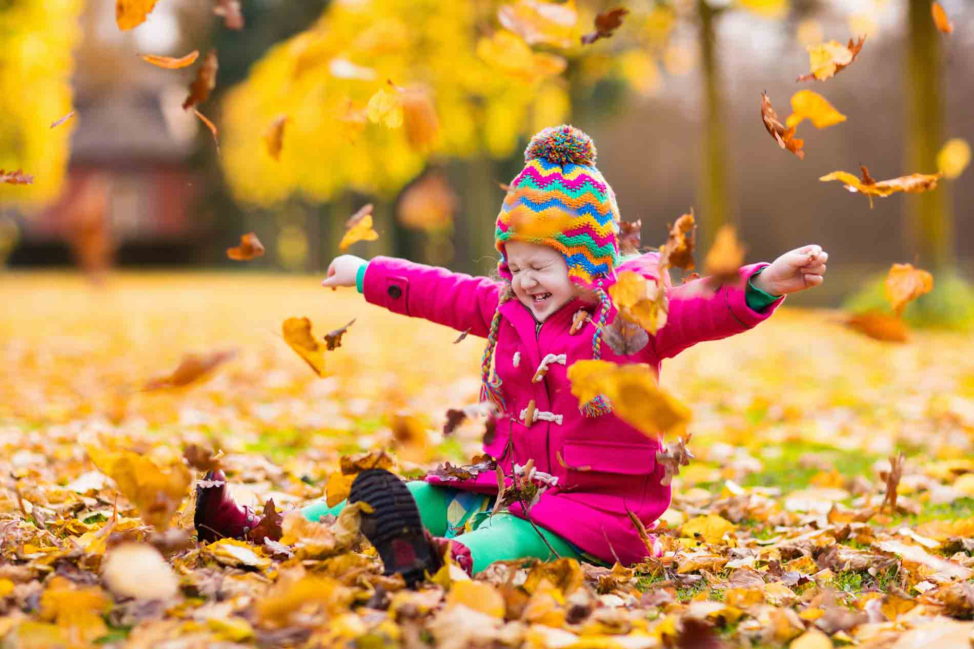 toddler playing in the leaves