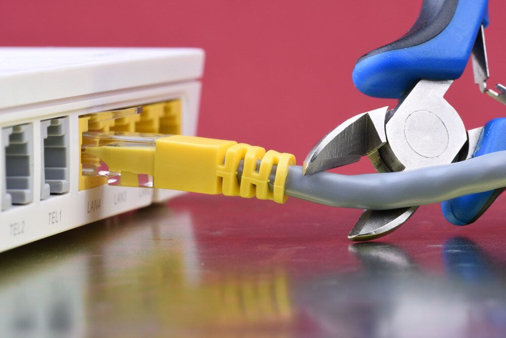 A Pair of Pliers is Cutting a Yellow Ethernet Cable — DGC Tech Solutions In Mareeba, QLD