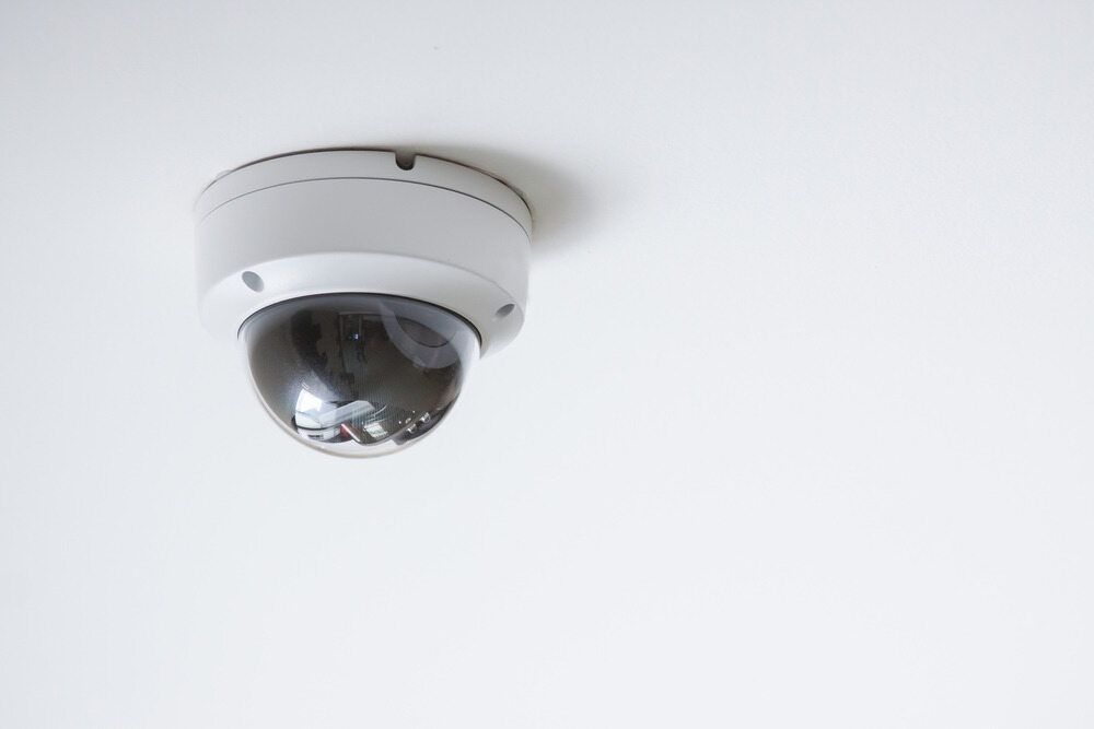 A Security Camera is Hanging From the Ceiling on a White Wall — DGC Tech Solutions In Mareeba, QLD