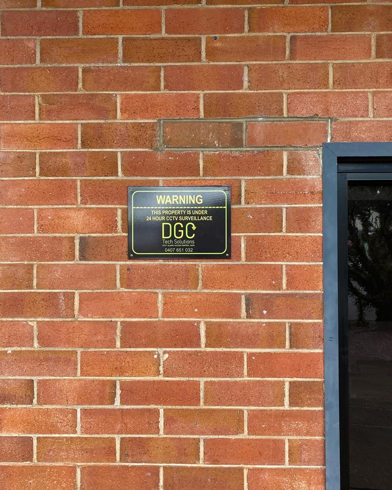 A Brick Wall With a Warning Sign on It — DGC Tech Solutions In Mareeba, QLD