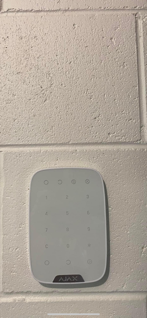 A White Remote Control is Mounted on a White Brick Wall — DGC Tech Solutions In Mareeba, QLD