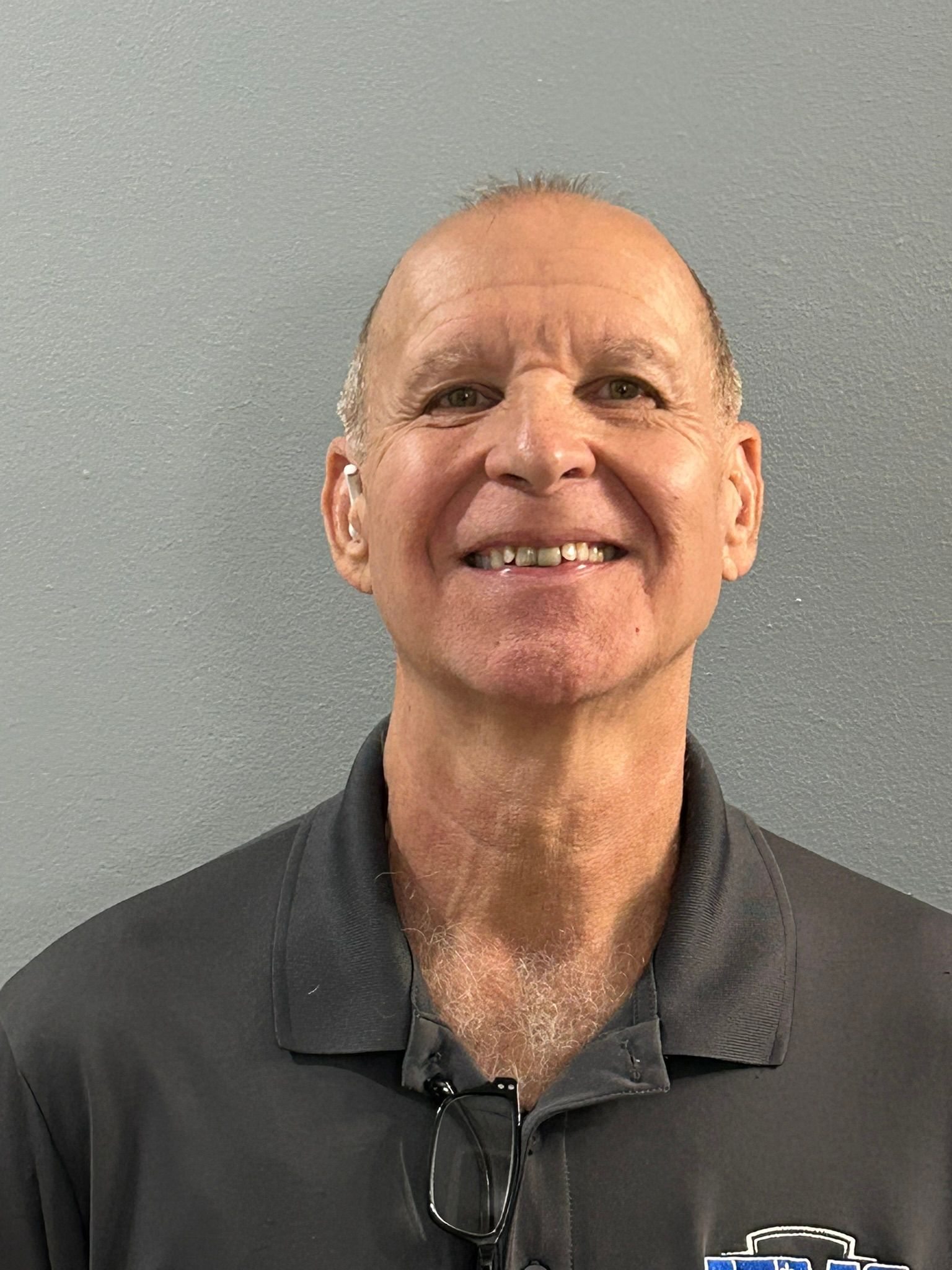 Man in gray shirt smiling, against a light gray background.