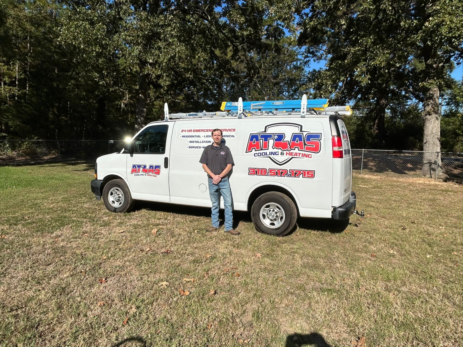 Two men stand beside a white Atlas Plumbing van outdoors.