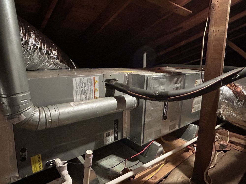 HVAC unit in an attic with ductwork, electrical wiring, and wooden beams.