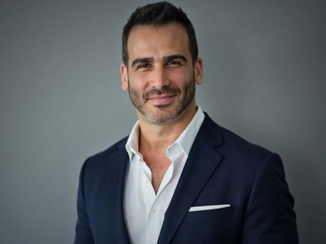 A man in a suit and white shirt is smiling for the camera.