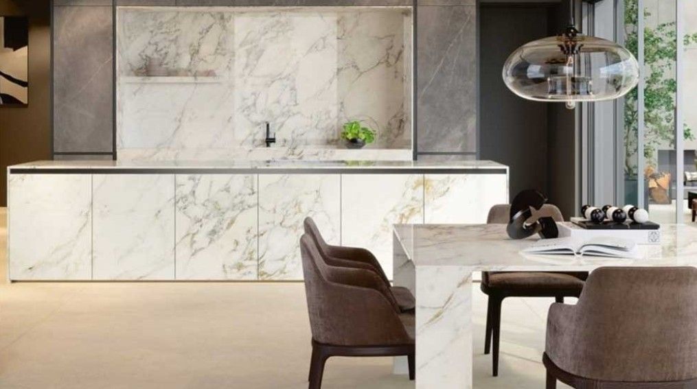 A kitchen with marble counter tops , a table and chairs.