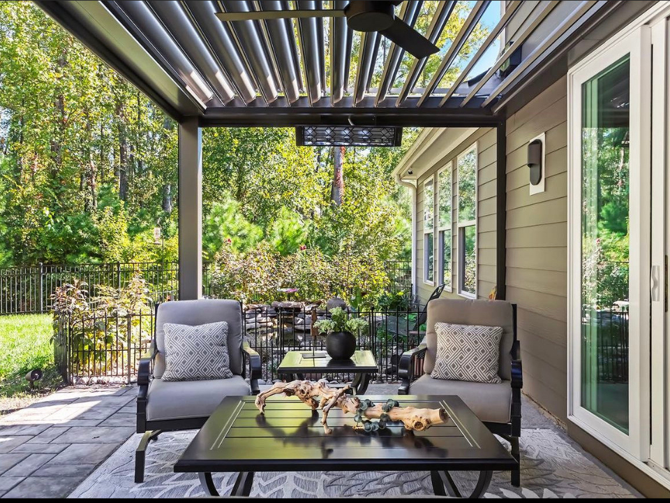 There is a large swimming pool in the backyard of a house with a motorized pergola