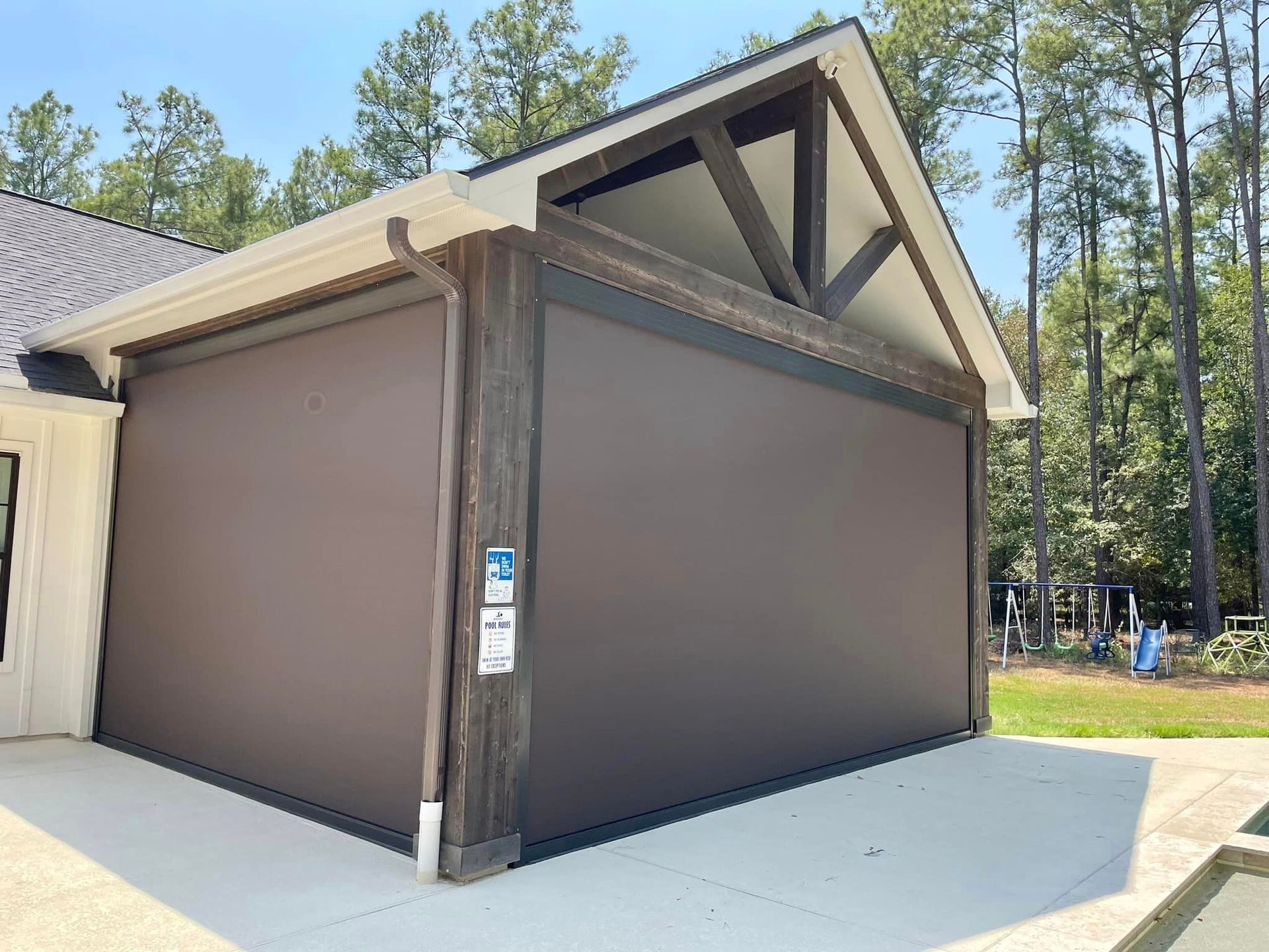 A large brown garage door is sitting next to a house.