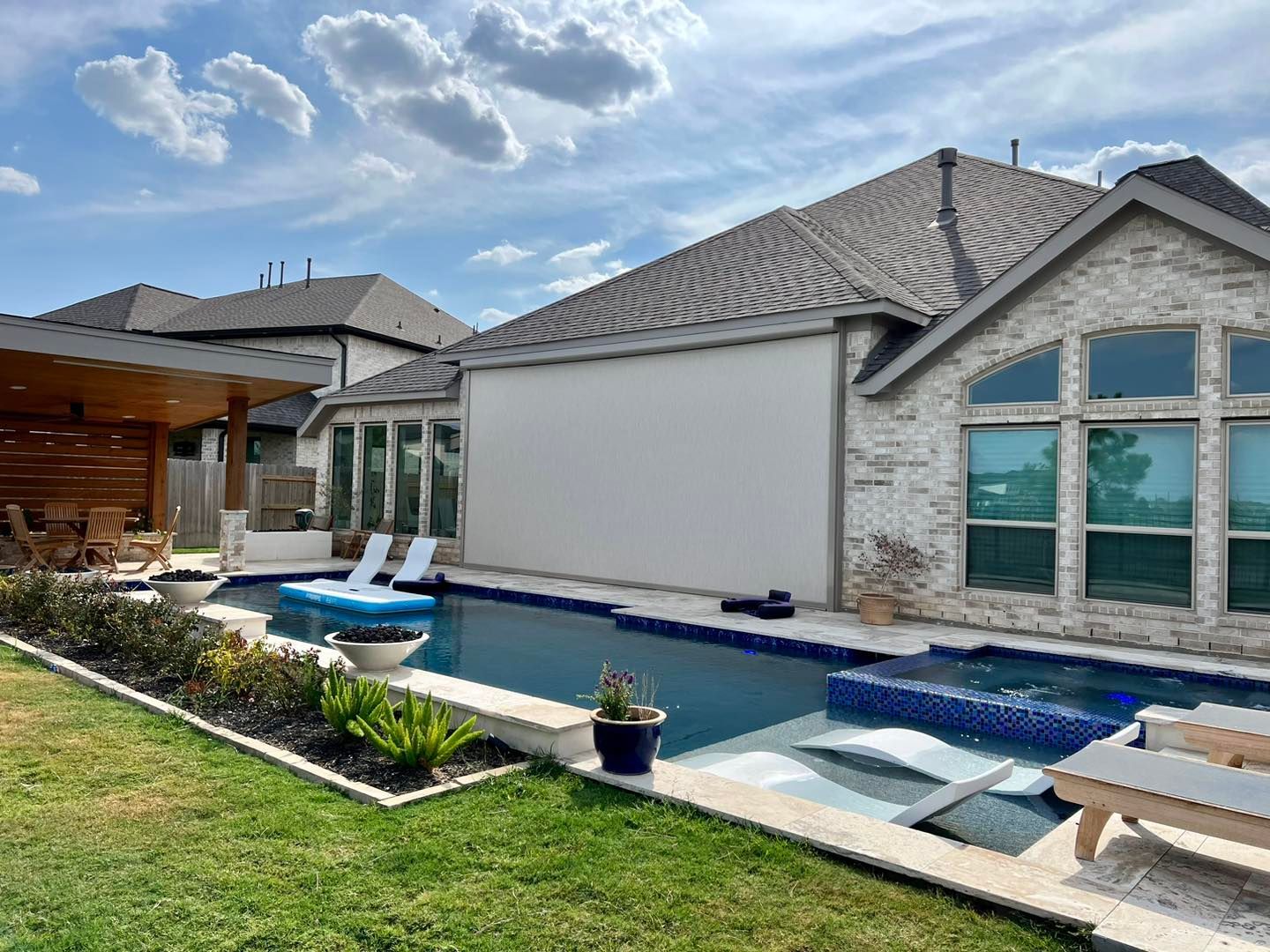 A large swimming pool is in the backyard of a house.