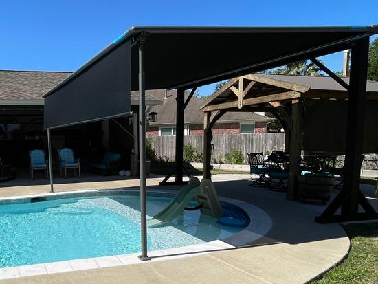 There is a large swimming pool in the backyard of a house with a motorized pergola
