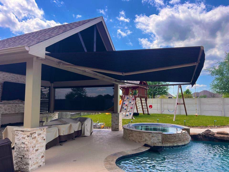 There is a swimming pool in the backyard of a house with an awning over it.
