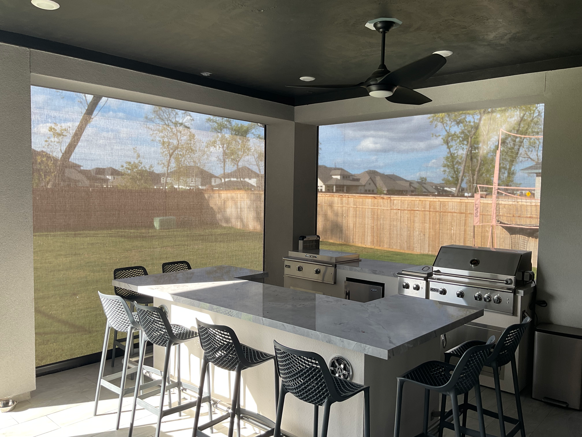 A patio with a table and chairs and a ceiling fan.