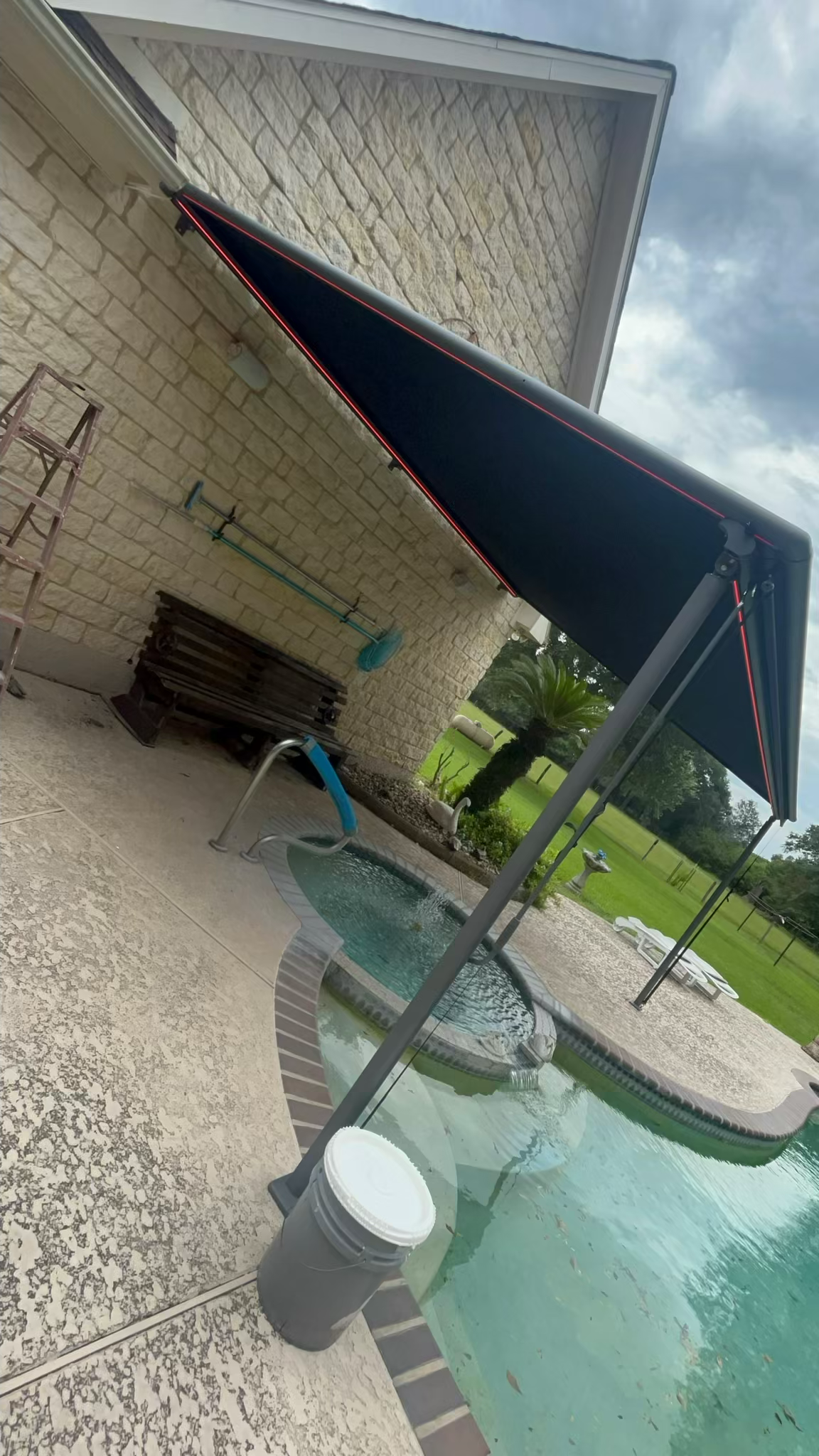 A patio with a canopy over a swimming pool.
