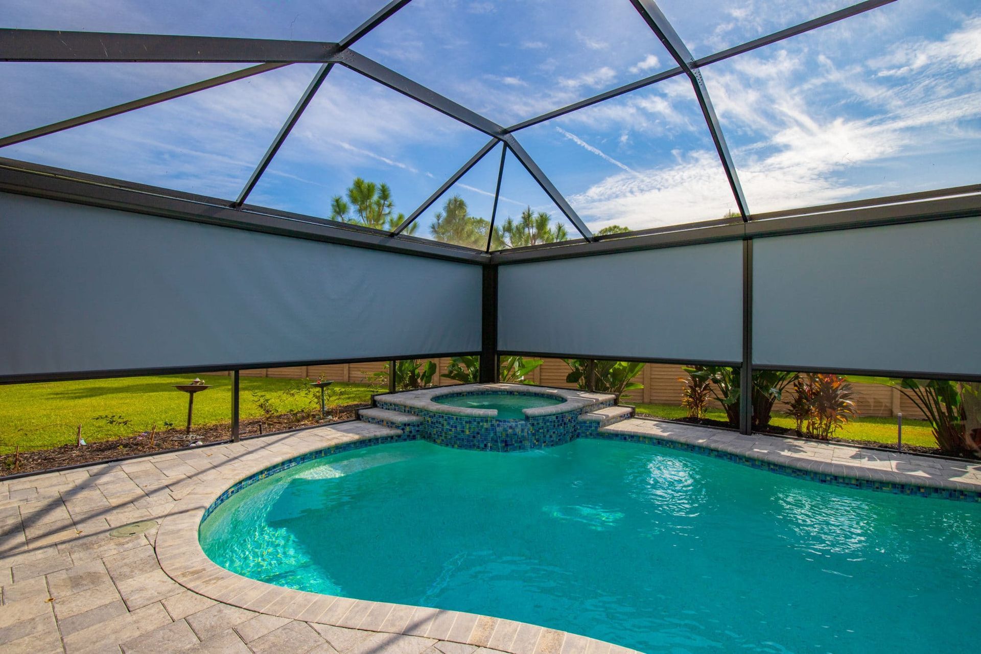 A large swimming pool surrounded by a screened in area.