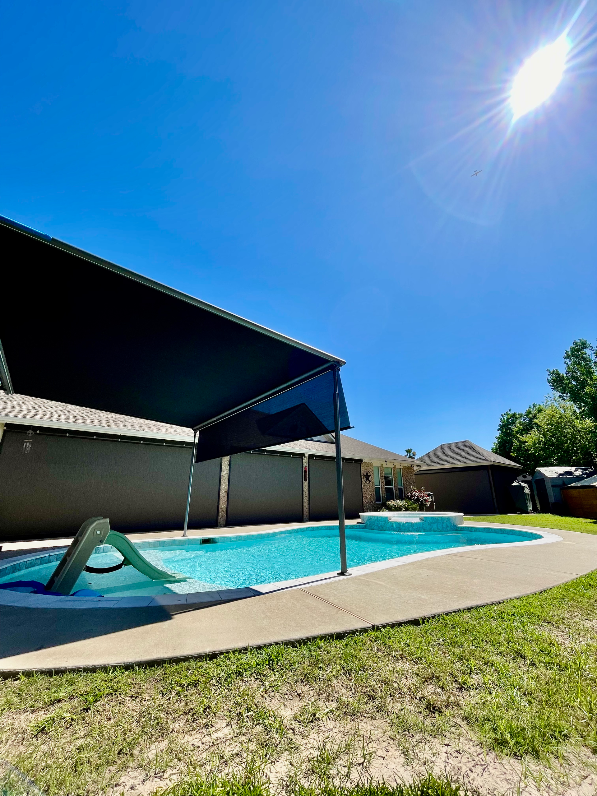 A large swimming pool with a black awning over it