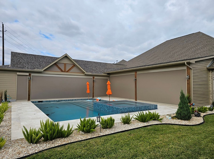 large swimming pool in the backyard of a house with motorized patio shades texas