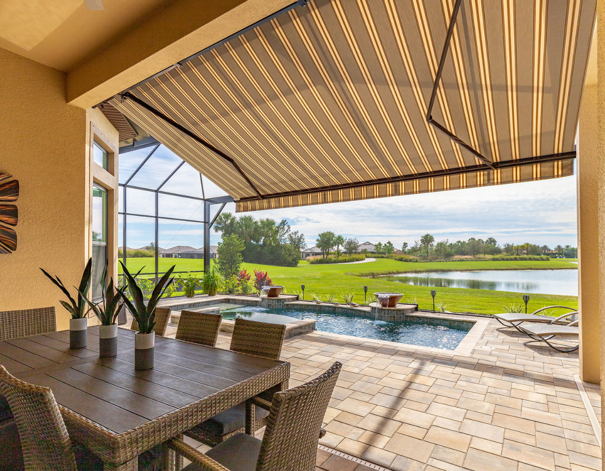 There is a large swimming pool in the backyard of a house with a motorized pergola