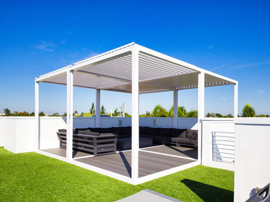 There is a large swimming pool in the backyard of a house with a motorized pergola