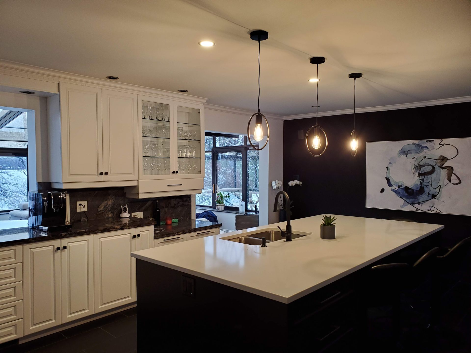 Une cuisine avec des armoires blanches, des comptoirs noirs et un grand îlot.