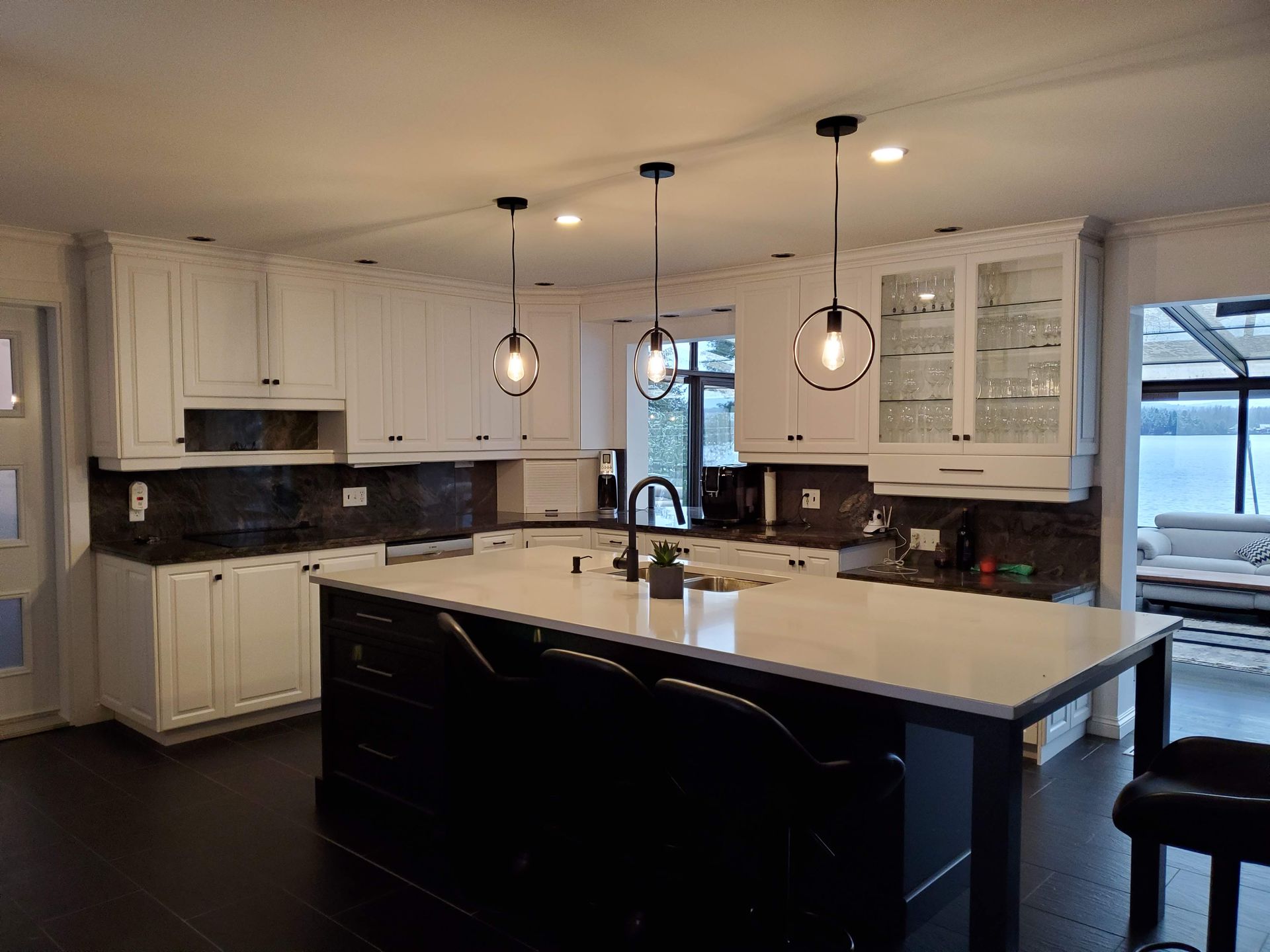 Une cuisine avec des armoires blanches, des comptoirs noirs et un grand îlot.