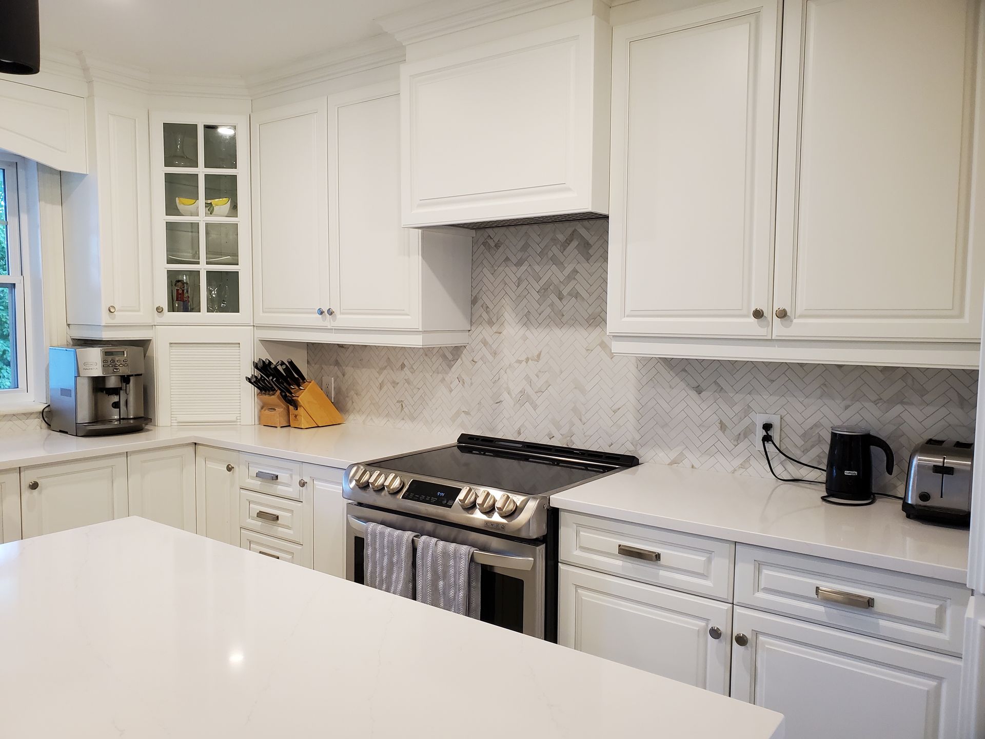 Une cuisine avec des armoires blanches, une cuisinière et un four grille-pain.