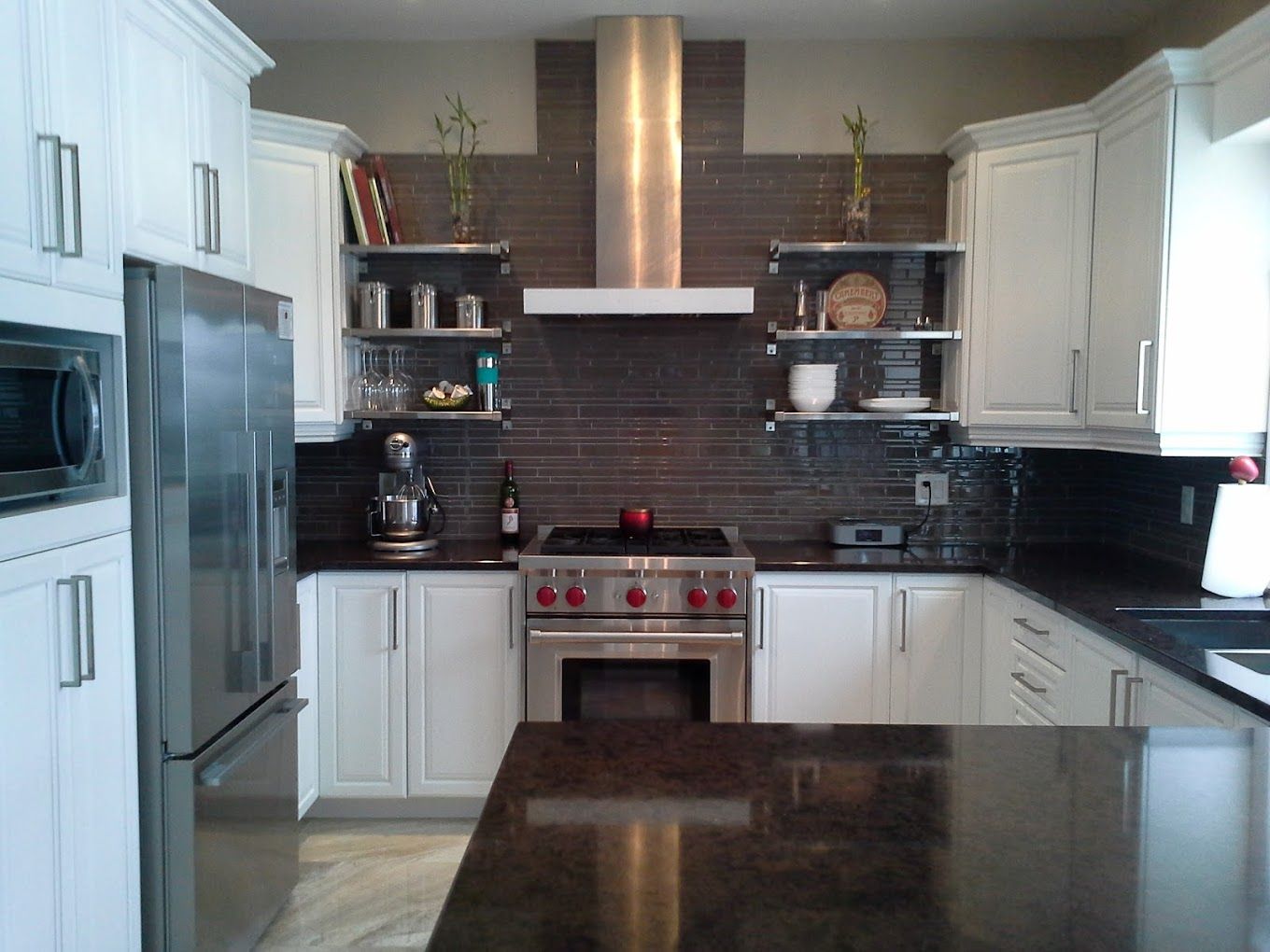 Une cuisine avec des armoires blanches et des appareils électroménagers en acier inoxydable