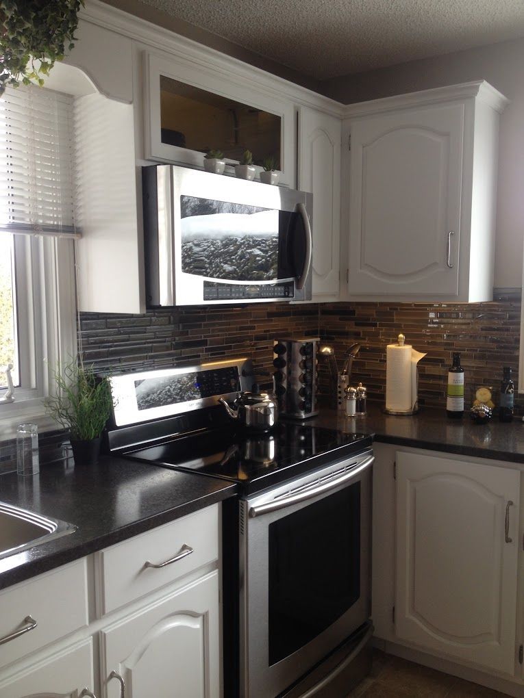 Une cuisine avec des appareils électroménagers en acier inoxydable et des armoires blanches