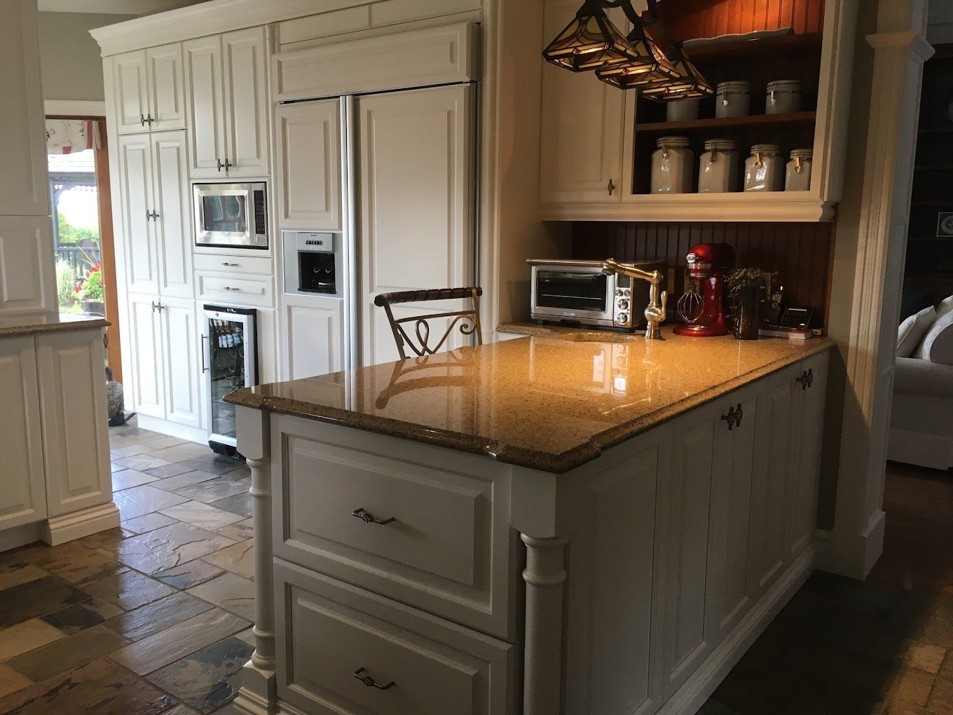 Une cuisine avec armoires blanches et comptoirs en granit