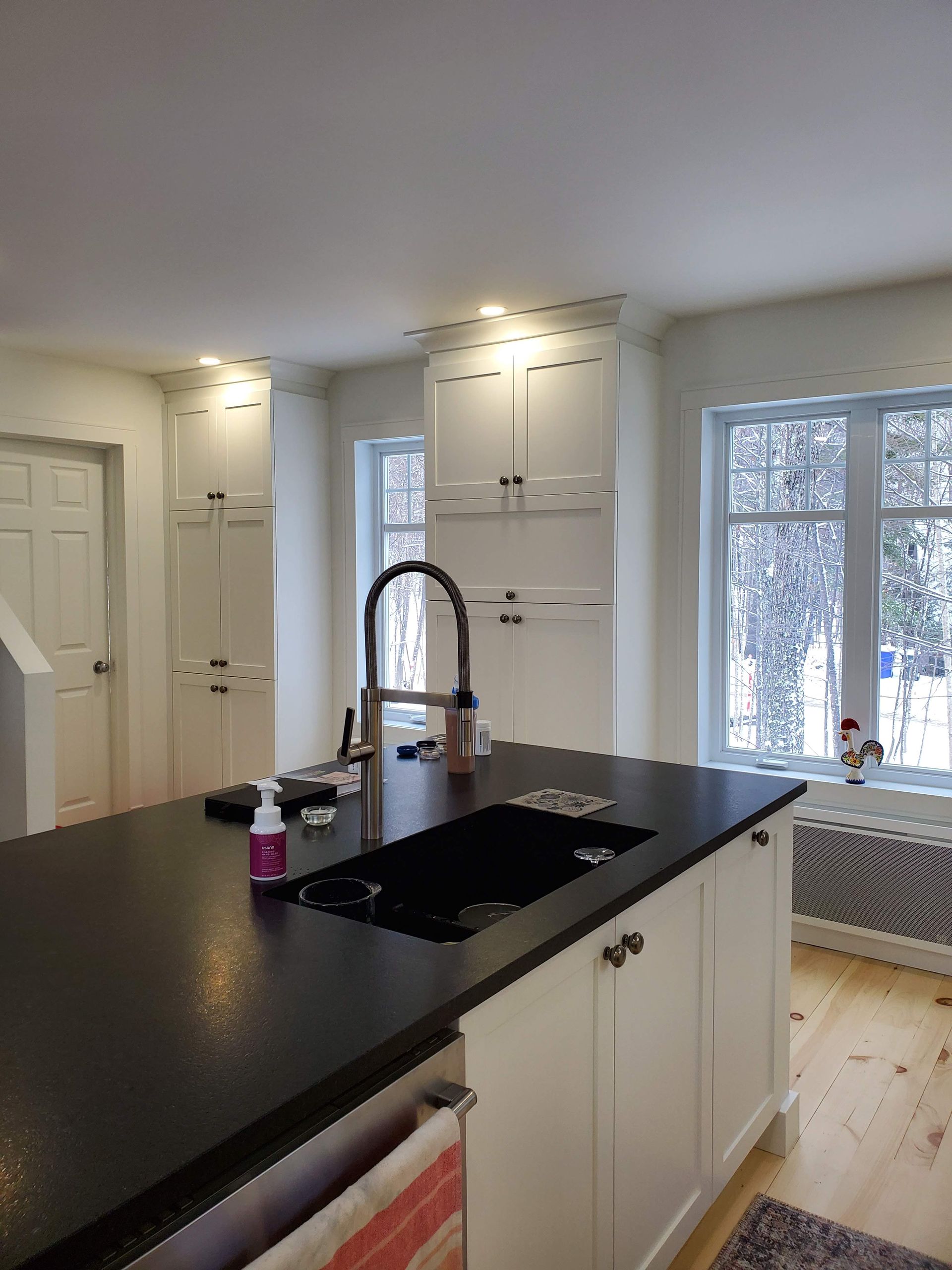 Une cuisine avec des armoires blanches et un comptoir noir avec un évier.
