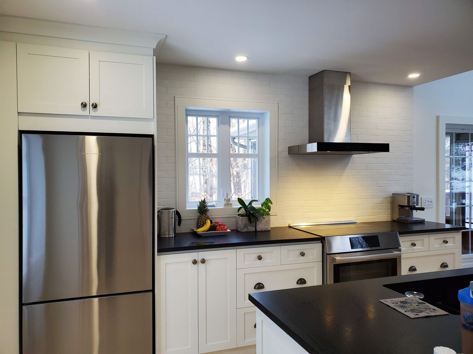 Une cuisine avec des appareils électroménagers en acier inoxydable et des armoires blanches