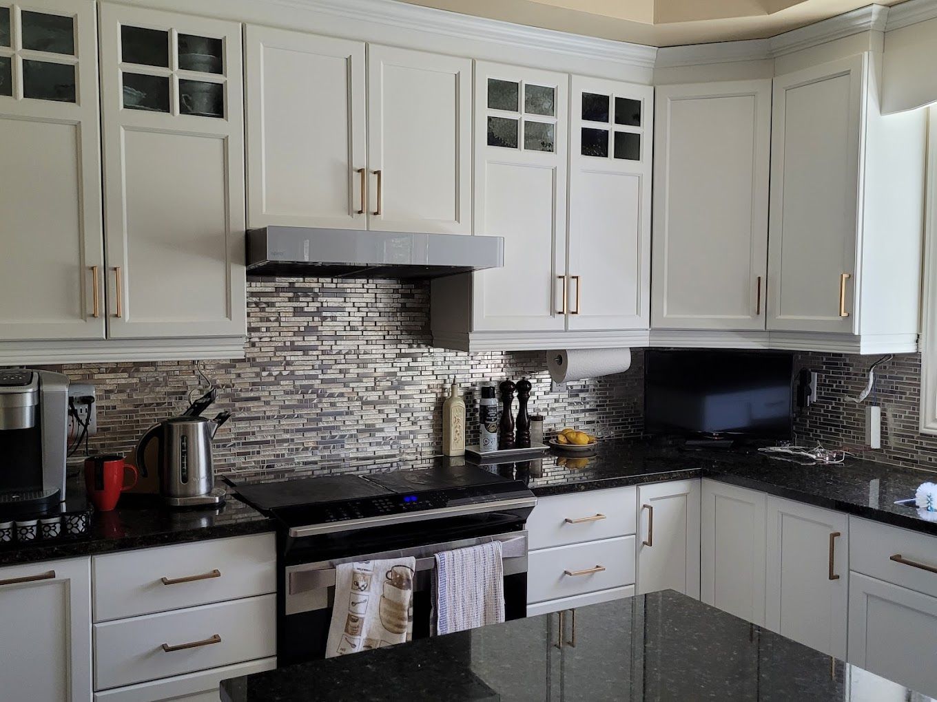 Une cuisine avec des armoires blanches et des comptoirs noirs